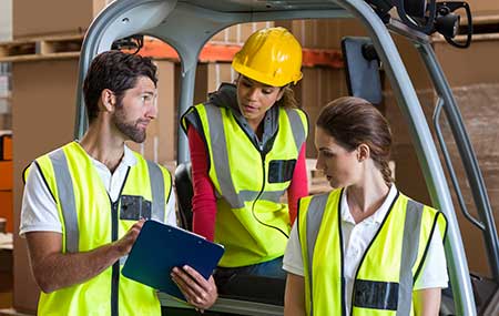 an instructor giving instructions to two trainee about Forklift